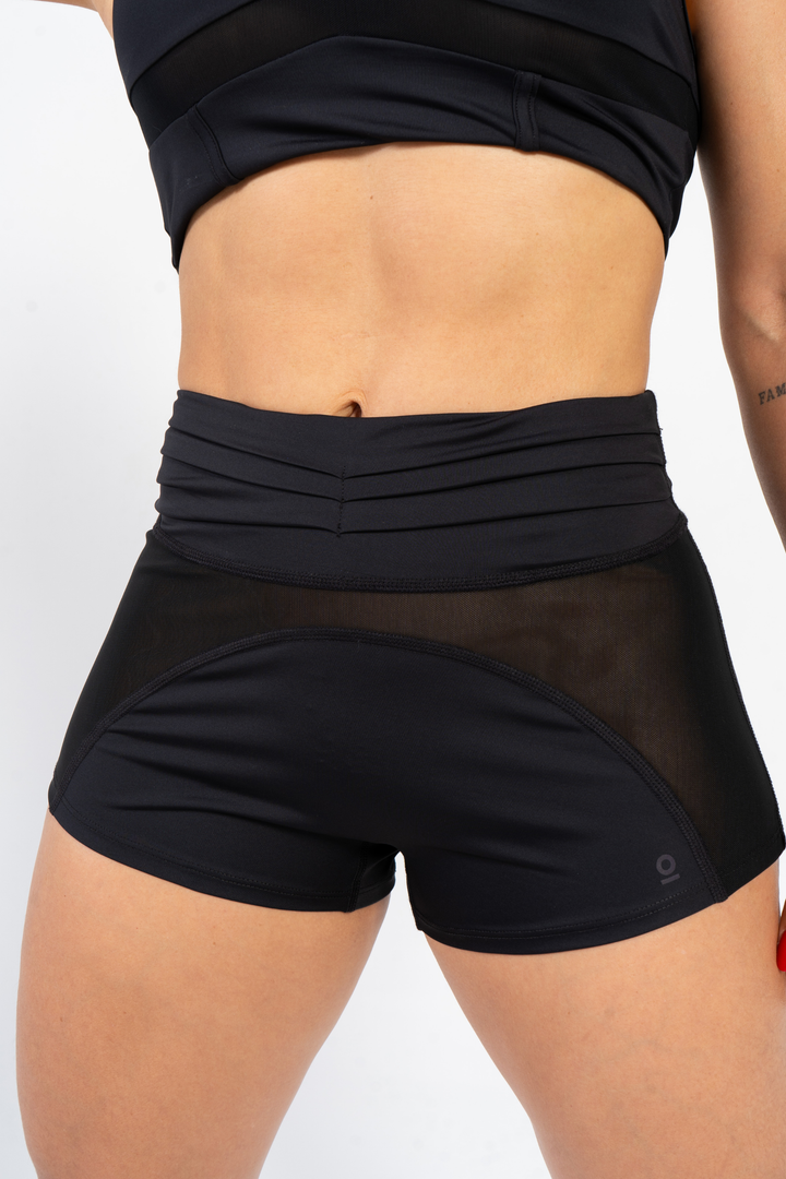 Person wearing black athletic shorts and top on a light gray background 