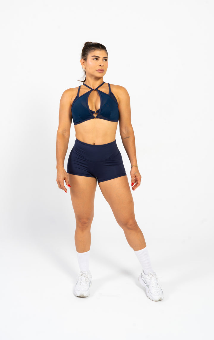 Woman wearing a navy sports bra and shorts set on a white background 