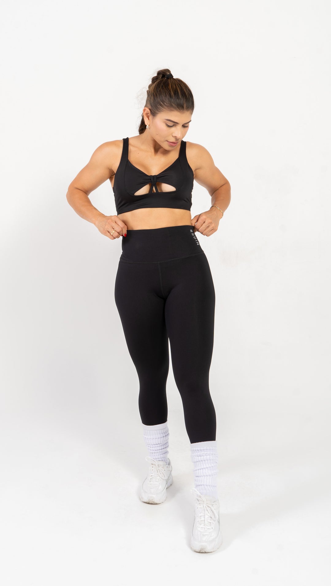 Woman wearing black athletic top and leggings on a white background 