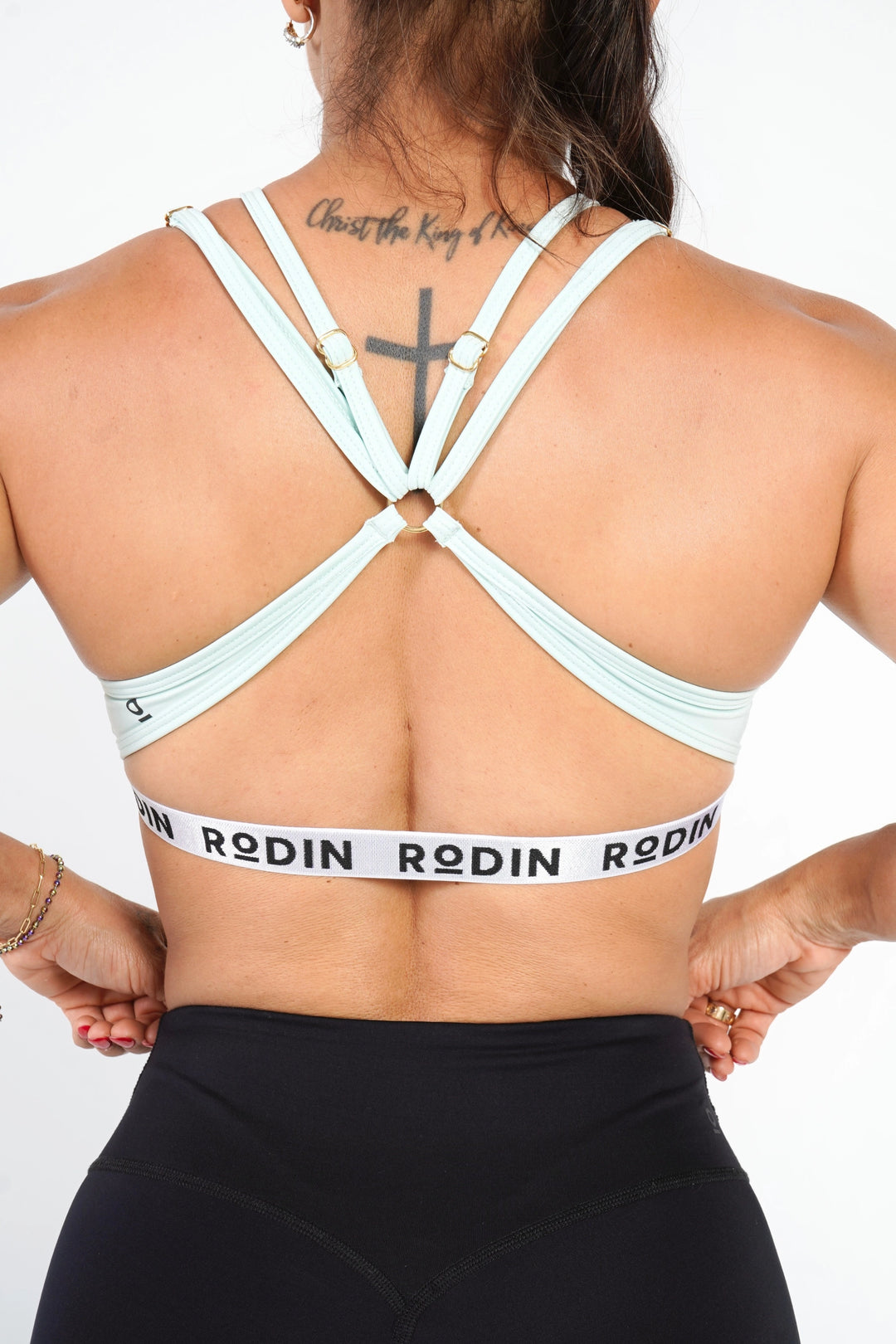 Person wearing a light green sports bra with 'Rodin' branding on a white background #color_mint