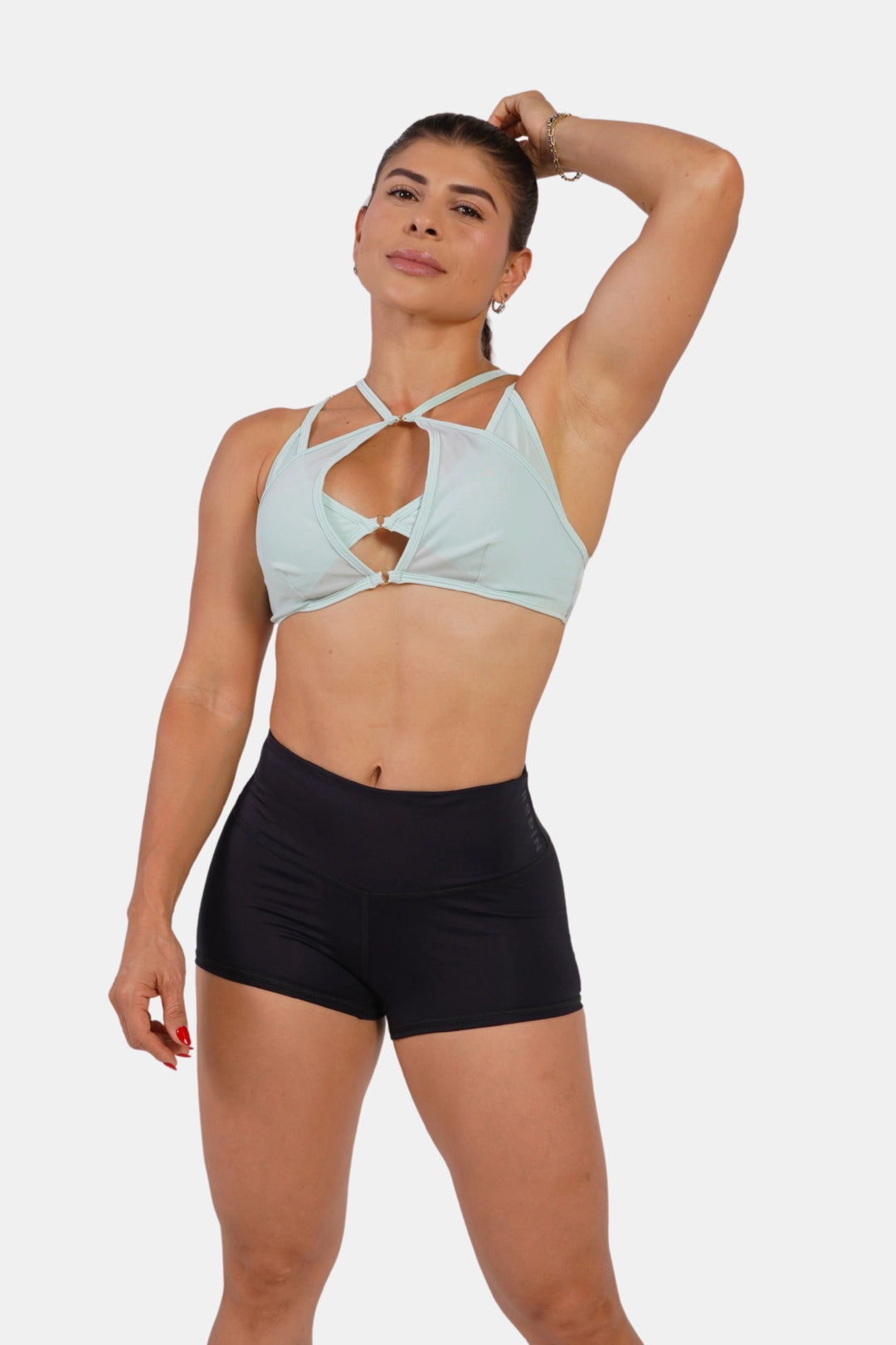 Woman wearing a light blue sports bra and black shorts on a white background  #color_mint