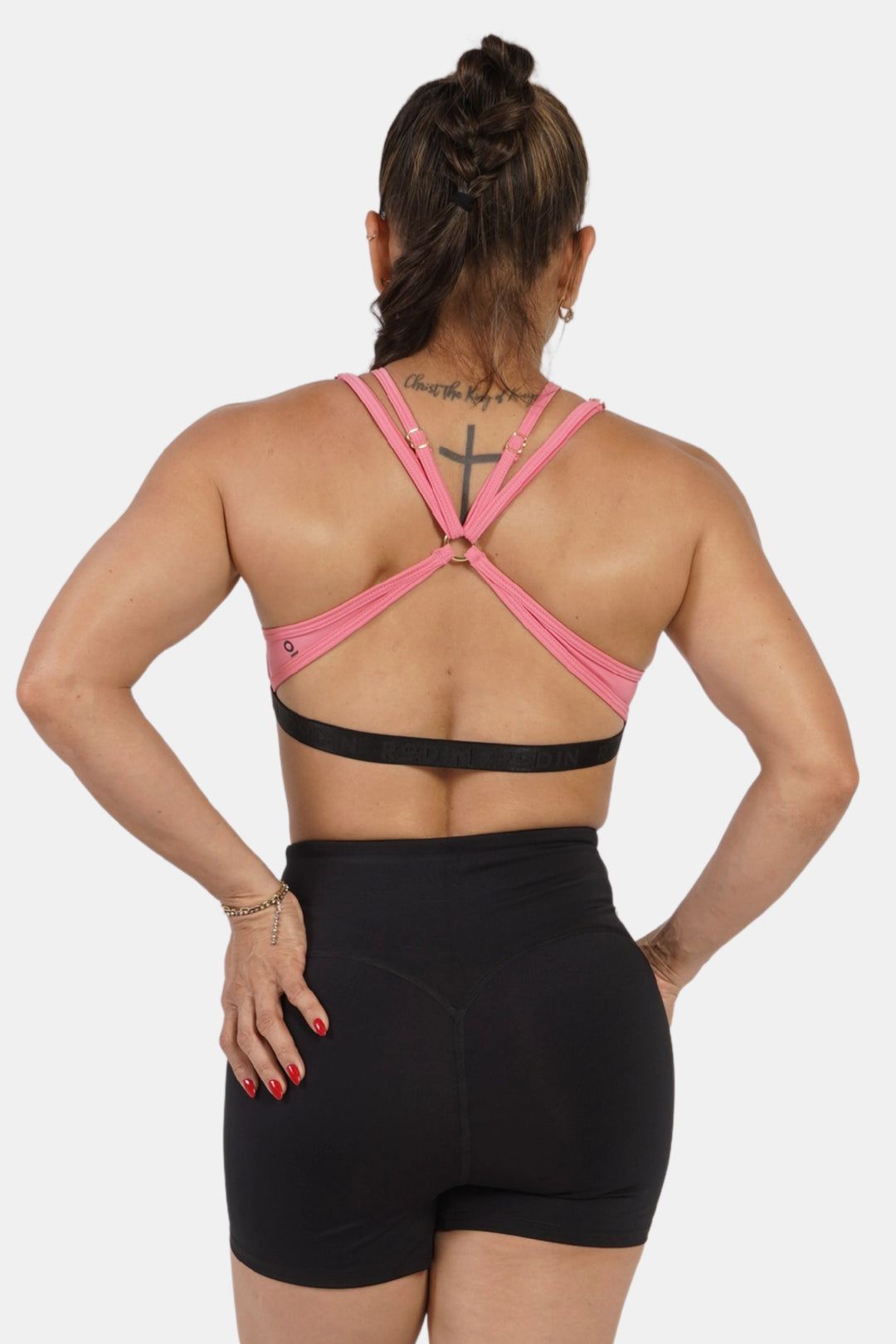 Person wearing a pink sports bra and black shorts on a white background #color_rose