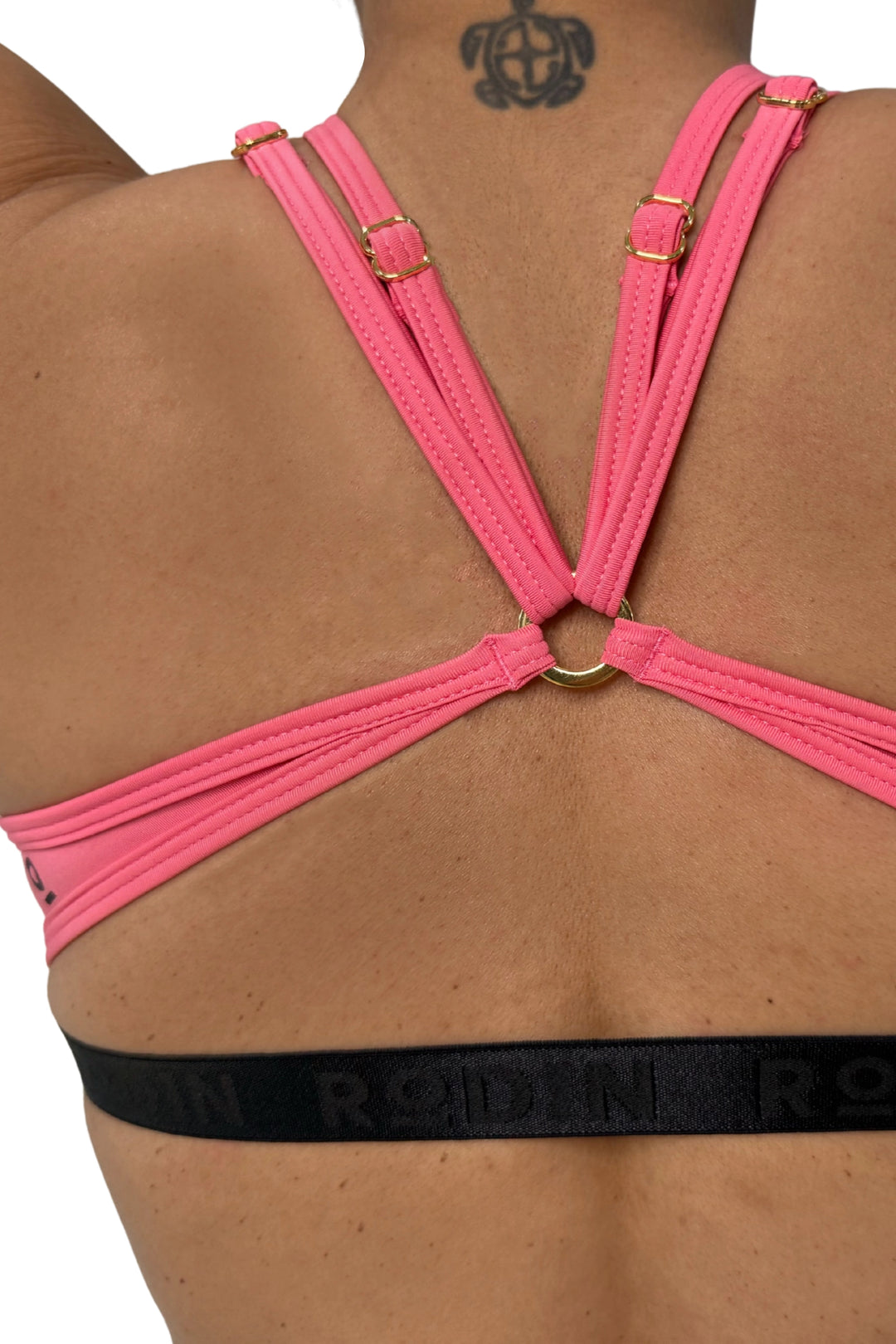 Rose Pink sports bra worn by a woman on a white background #color_rose