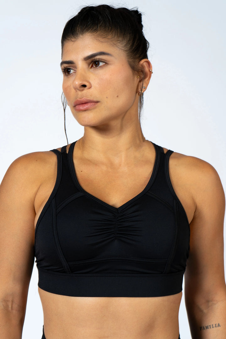 Woman wearing a black sports bra against a light gray background #color_black