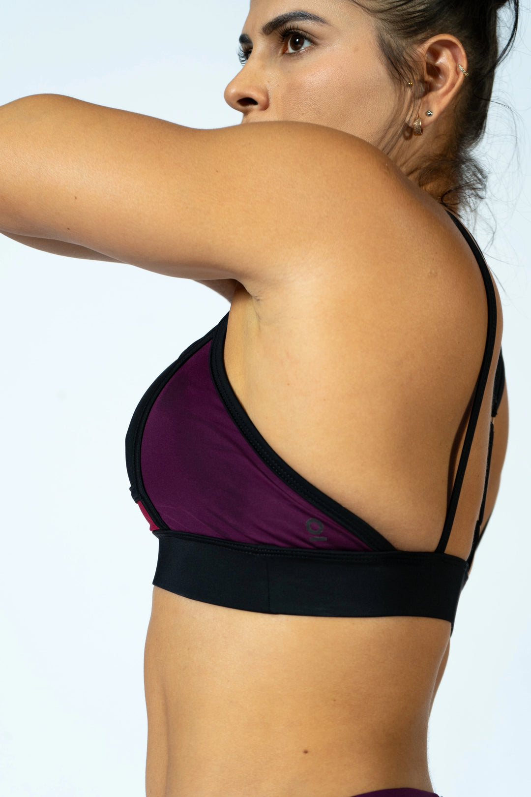 Woman wearing a black and magenta sports bra against a light gray background. #color_black-magenta