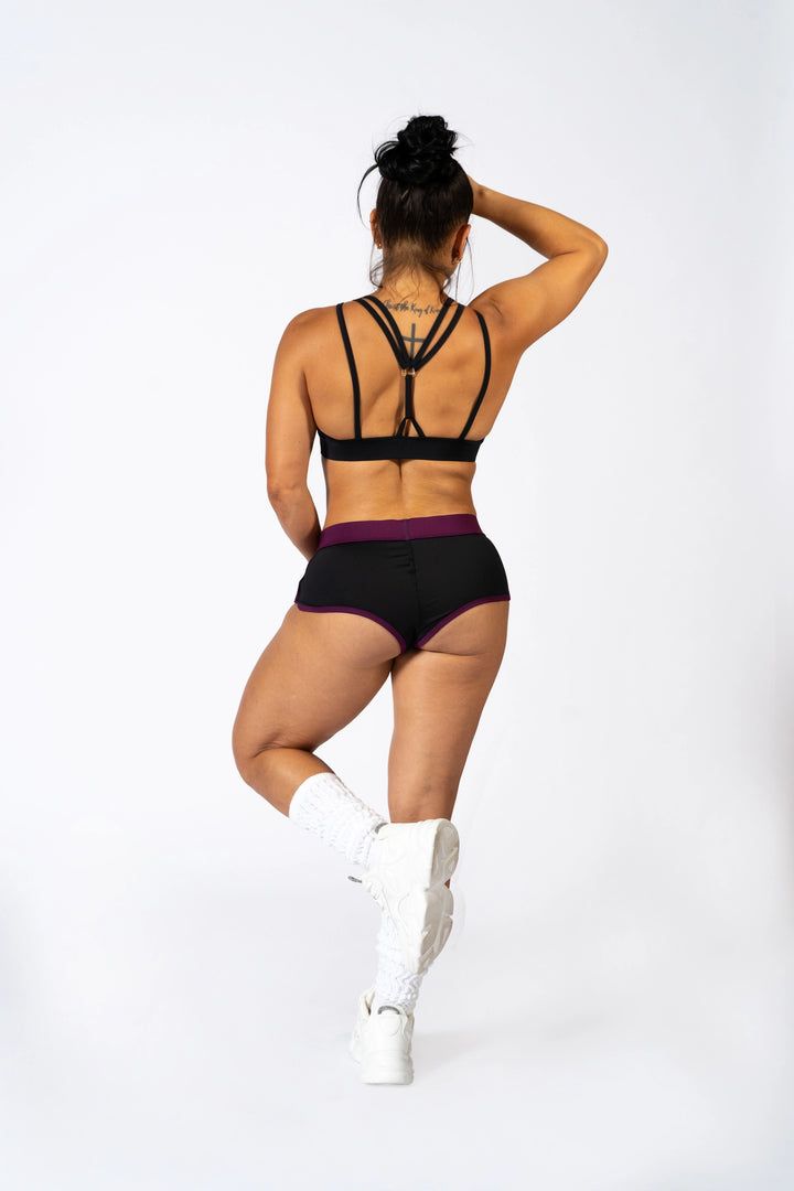 Woman wearing a black sports bra and shorts on a white background  #color_black-magenta