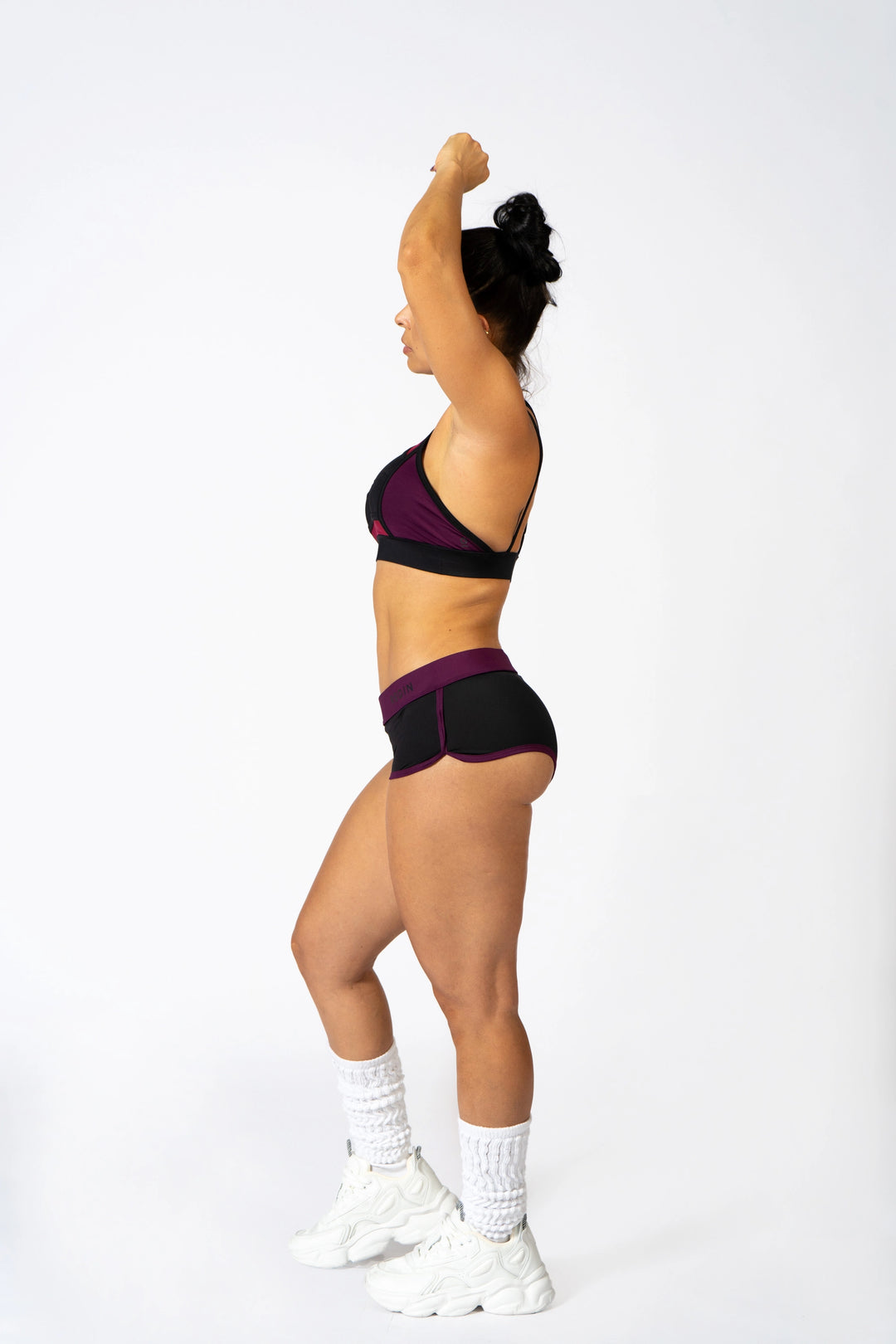 Person wearing a black and purple sports bra and shorts on a white  background  #color_black-magenta