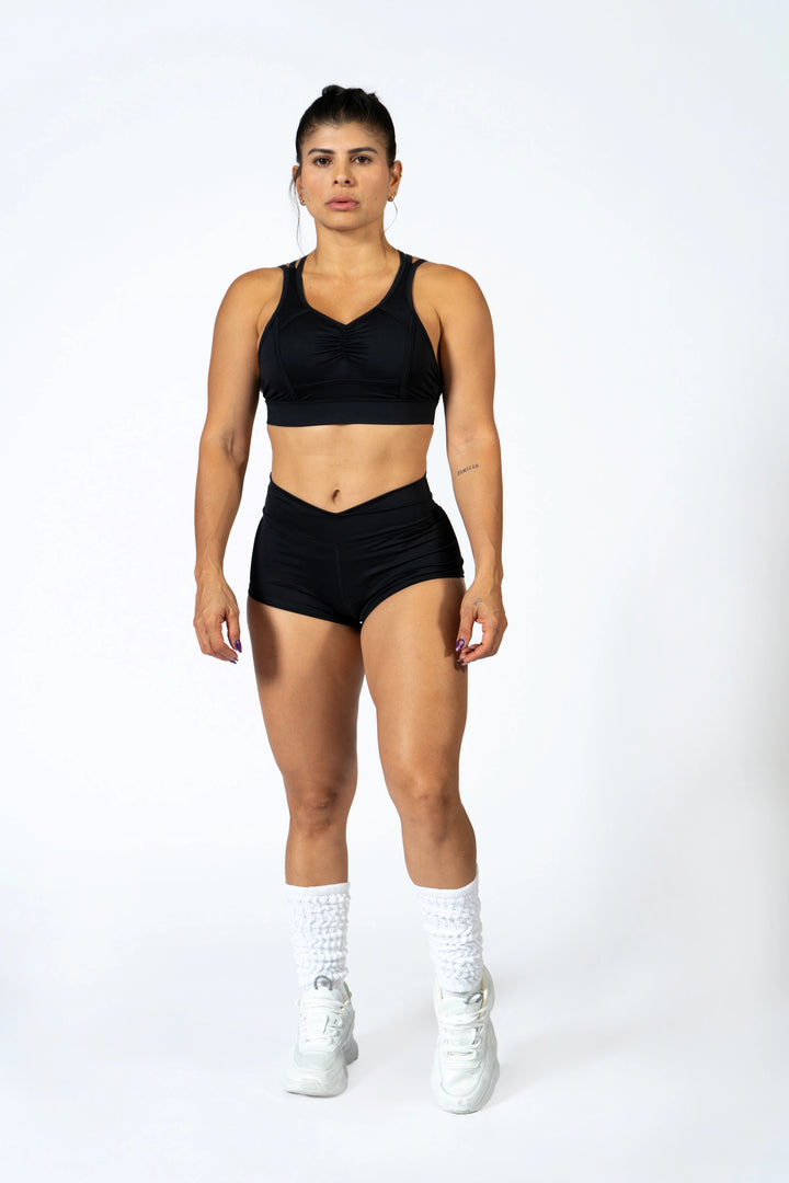 Woman wearing a black sports bra and shorts with white socks and shoes on a white background #color_black