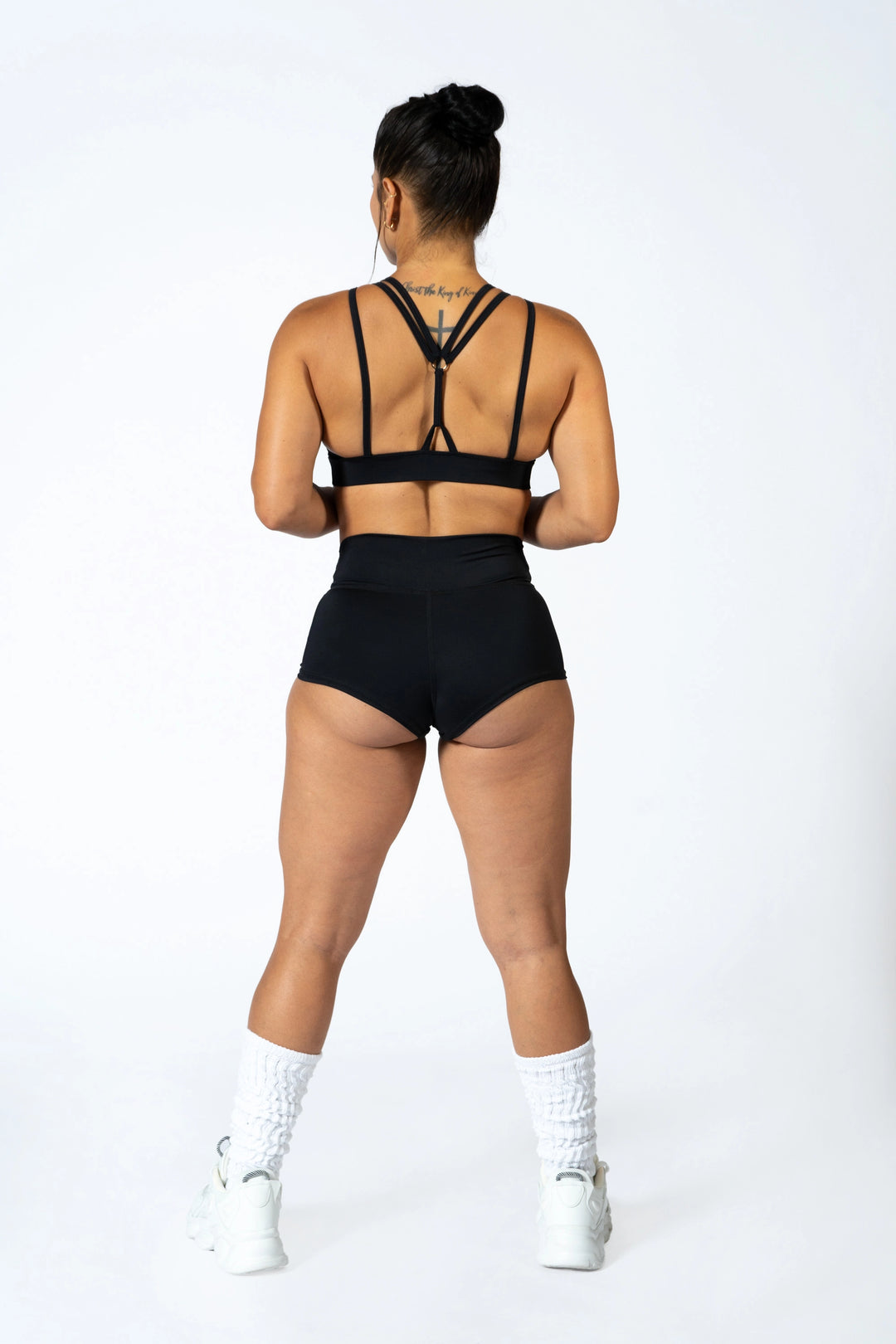 Person wearing a black sports bra with black shorts on a white background #color_black