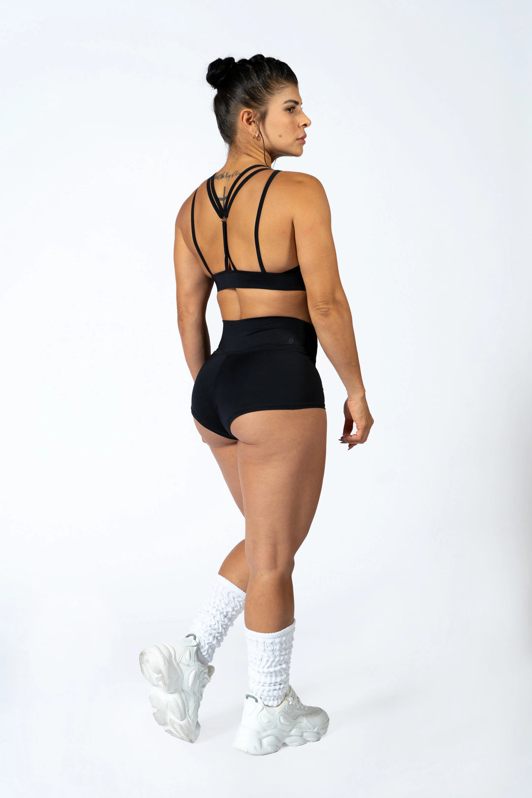 Woman wearing a black sports bra and shorts set on a white background  #color_black