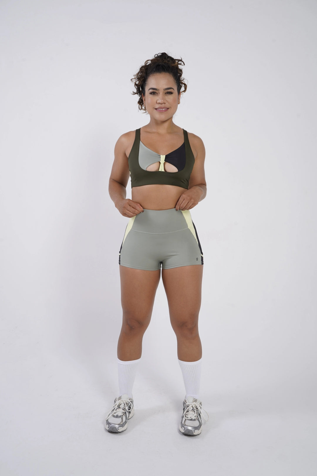 Woman wearing a green sports bra and shorts on a white background  #color_riffle-green