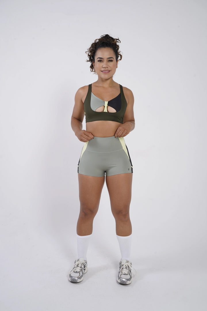 Woman wearing a green sports bra and shorts on a white background  #color_riffle-green