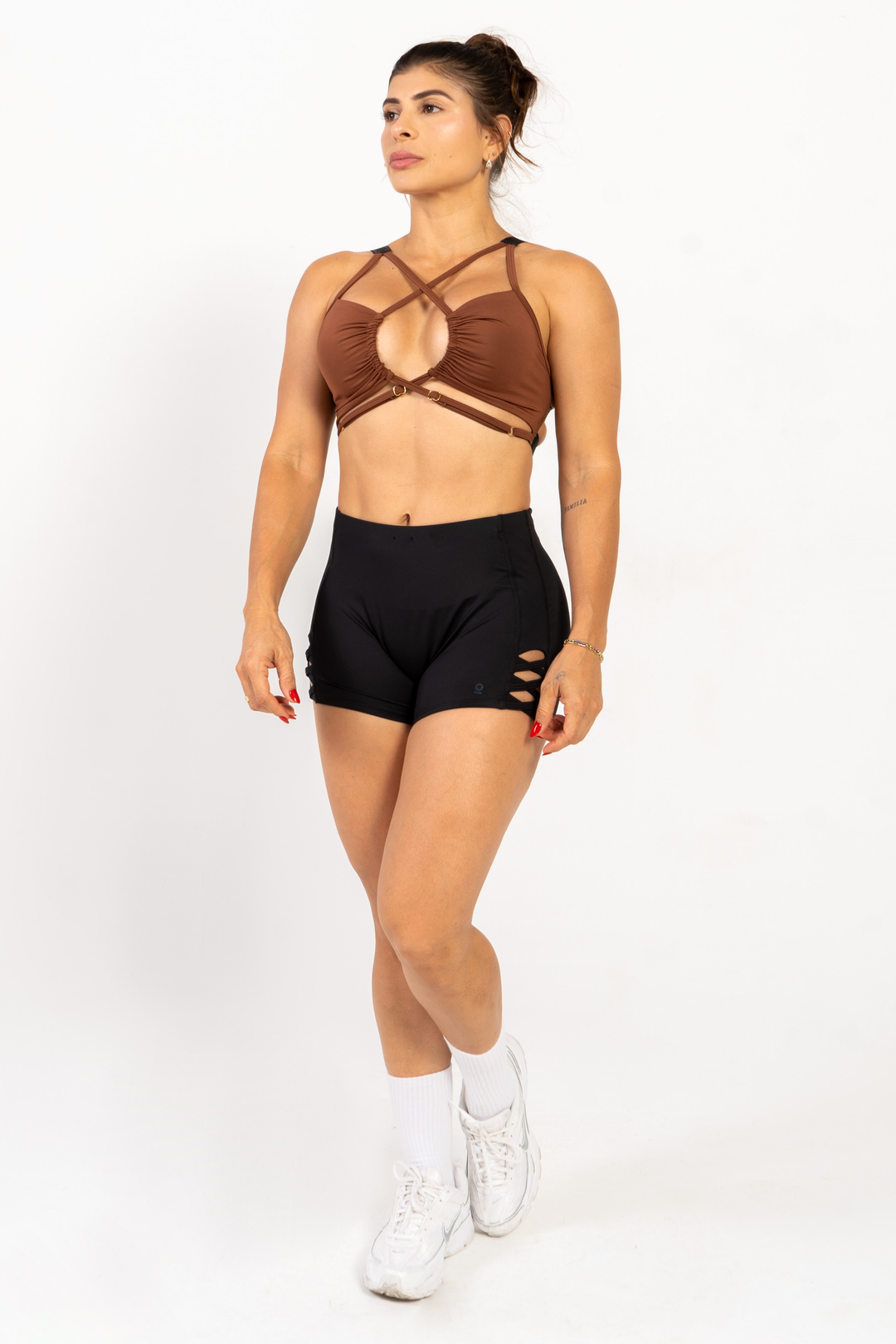 Woman wearing a brown sports bra and black shorts on a white background 