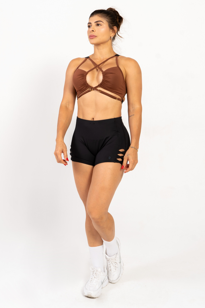Woman wearing a brown sports bra and black shorts on a white background 