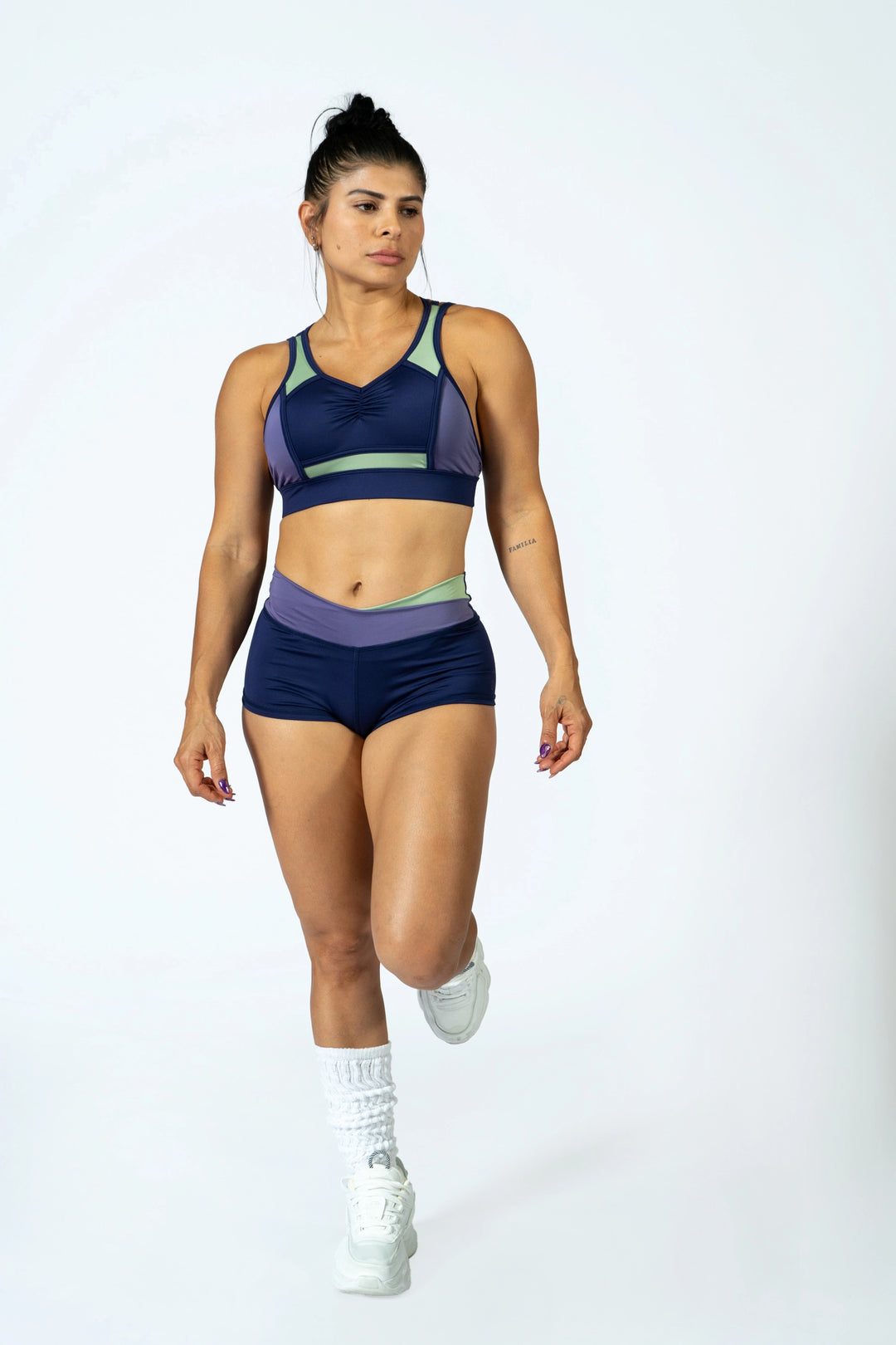Woman wearing a sports bra and shorts on a white background #color_iris-mystical-basil