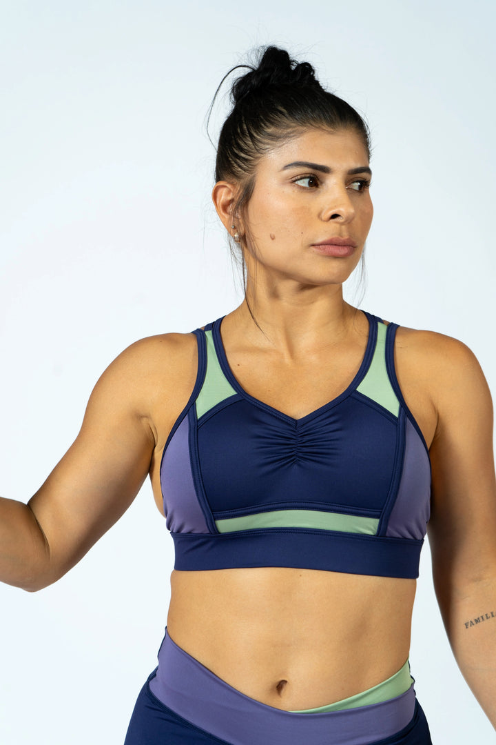 Woman wearing a sports bra and leggings on a plain background #color_iris-mystical-basil