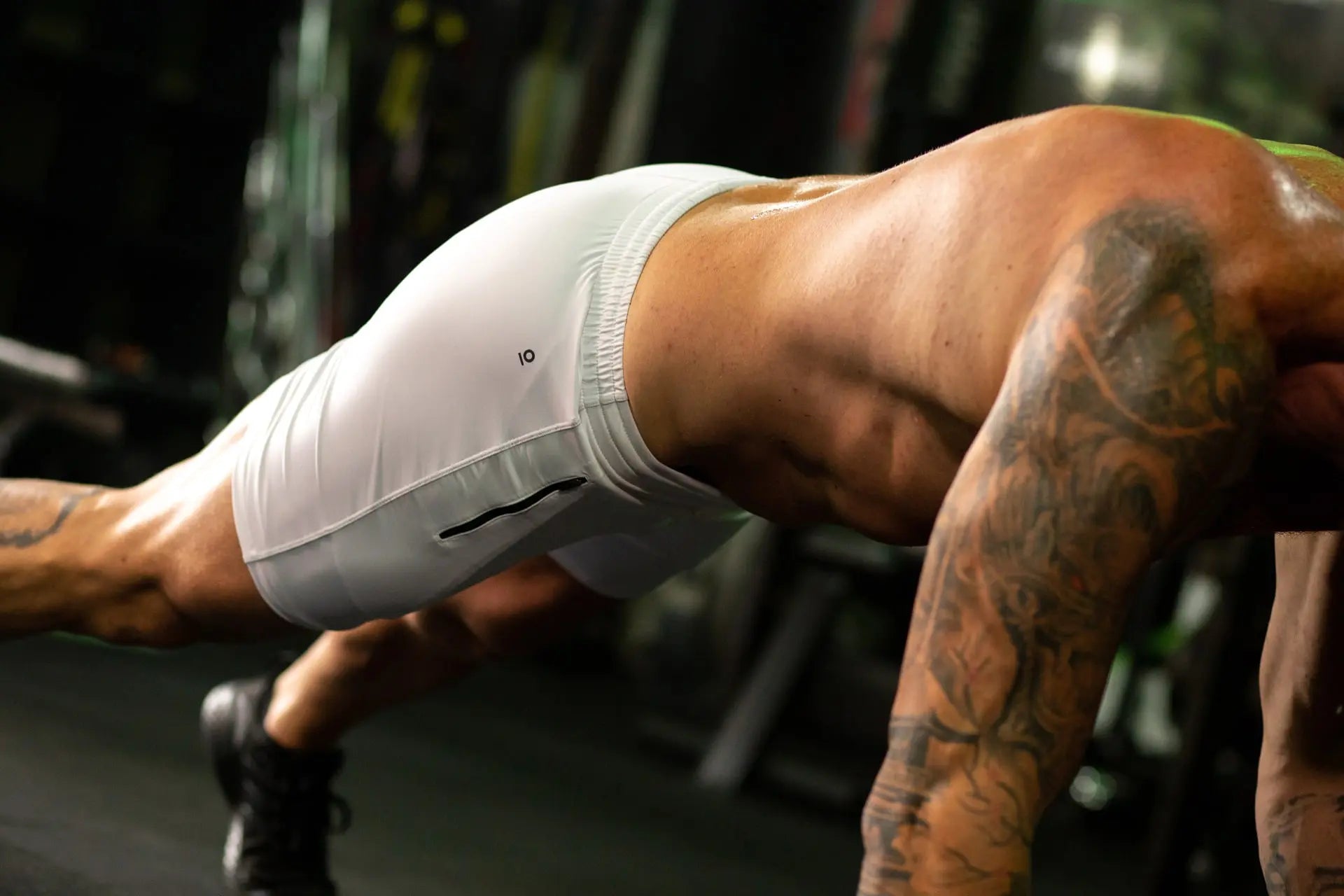 Man athlete in white shorts backside doing a plank